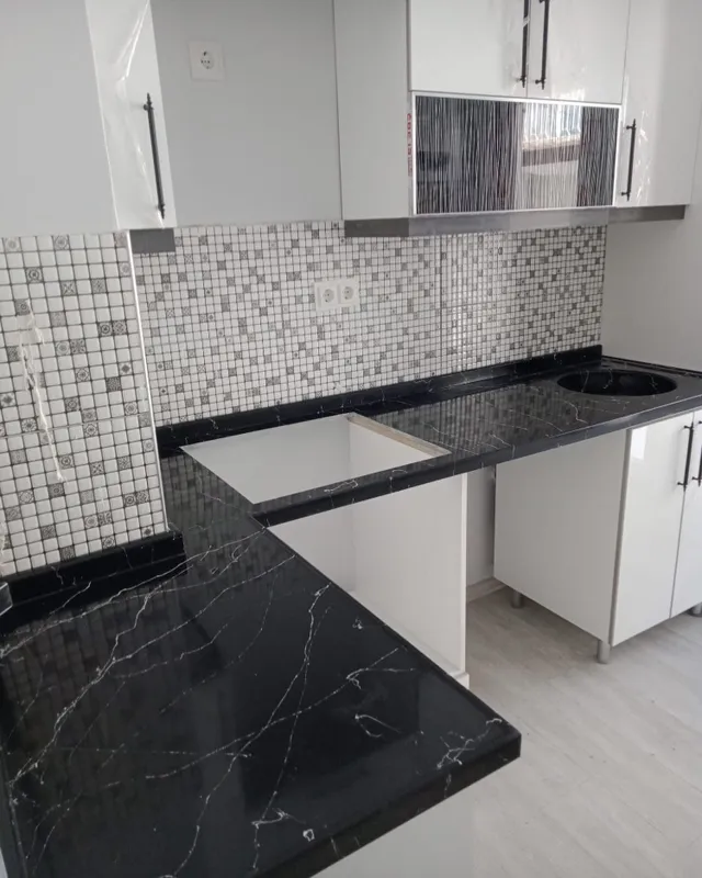 Beyaz mutfak dolapları üzerinde açık damarlı koyu renk L tezgâh